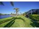 Expansive waterfront backyard featuring lush green grass, tropical palm trees, and a screened-in patio at 955 Don Juan Ct, Punta Gorda, FL 33950