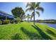 Backyard view features a screened lanai, lush lawn, palm trees, and canal at 955 Don Juan Ct, Punta Gorda, FL 33950