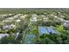 An aerial view of a quiet neighborhood with many trees, a playground, basketball court, and tennis courts at 1065 Harbour Glen Pl, Punta Gorda, FL 33983