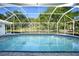A screened-in pool and clear blue water are surrounded by trees and foliage at 1065 Harbour Glen Pl, Punta Gorda, FL 33983
