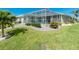 The backyard features a screened-in lanai with a pool, lush green grass, and landscaping at 1311 Pine Siskin Dr, Punta Gorda, FL 33950