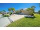 Well-manicured lawn, mature palms and landscaping complement the paver driveway leading to the attached garage at 1311 Pine Siskin Dr, Punta Gorda, FL 33950