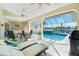 Relaxing covered lanai with lounge chairs, a dining table, and a pool with water views at 1311 Pine Siskin Dr, Punta Gorda, FL 33950