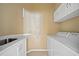 Well-lit laundry room with white cabinets, countertop, sink and decorative wall art at 16308 Sunset Palms Blvd # 1702, Punta Gorda, FL 33955