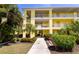 Inviting yellow condominium building featuring well-maintained landscaping and pedestrian walkway at 2060 Willow Hammock Cir # 207, Punta Gorda, FL 33983