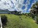 Expansive backyard showcasing a lush, green hillside with tropical landscaping and blue skies at 2095 Ellery St, Port Charlotte, FL 33952