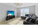 Bright living room features a gray sofa set, media center with a TV, and natural light from window at 2201 Birchcrest Blvd, Port Charlotte, FL 33952