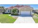Single-story home with a lush front lawn, two-car garage, and tropical landscaping leading to the front door at 341 Segovia Dr, Punta Gorda, FL 33950