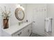 Bright bathroom boasts white cabinets, quartz counters, and a round mirror at 619 Boundary Blvd, Rotonda West, FL 33947
