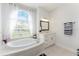Bright bathroom featuring a soaking tub under an arched window, vanity, and a tile floor at 619 Boundary Blvd, Rotonda West, FL 33947