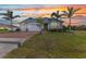 Charming single-story home featuring a brick driveway, two-car garage, and well-maintained lawn at sunset at 7028 N Plum Tree, Punta Gorda, FL 33955