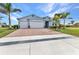 Charming blue home with a well-manicured lawn, brick-paved driveway, and a two-car garage at 7028 N Plum Tree, Punta Gorda, FL 33955