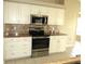 Updated kitchen with stainless steel range and microwave, granite countertops, and tile backsplash at 7500 Ligustrum, Punta Gorda, FL 33955