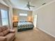 Bright bedroom featuring a ceiling fan, recliner, and two bedside tables with lamps at 10900 Lerwick Cir, Englewood, FL 34223