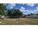 A backyard features a metal chair, mature trees, and a high fence under a sunny sky at 131 Spring Lake Nw Blvd, Port Charlotte, FL 33952