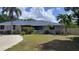 Charming home featuring a well-maintained lawn, mature trees, and a freshly painted exterior in a serene setting at 131 Spring Lake Nw Blvd, Port Charlotte, FL 33952