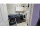 Well-lit laundry room with side by side washer and dryer and white cabinets for storage at 131 Spring Lake Nw Blvd, Port Charlotte, FL 33952