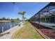 Scenic backyard view featuring a waterfront canal, lush lawn and enclosed pool with palm trees at 15538 Aqua Cir, Port Charlotte, FL 33981