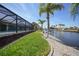 Lush backyard featuring a canal, a dock and pool with a screened lanai, great for outdoor activities at 15538 Aqua Cir, Port Charlotte, FL 33981