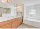 Bright bathroom featuring double sinks, a large mirror, a tub, and a separate glass shower at 15538 Aqua Cir, Port Charlotte, FL 33981