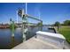 Waterfront property with a private dock and boat lift along a canal under a bright blue sky at 15538 Aqua Cir, Port Charlotte, FL 33981