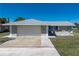 Front exterior features a light gray home, attached garage, and walkway to the front patio at 21168 Quesada Ave, Port Charlotte, FL 33952
