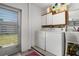 Laundry area featuring washer, dryer, and storage cabinets, with a door to the outside at 21168 Quesada Ave, Port Charlotte, FL 33952