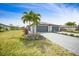 Inviting exterior elevation with a three-car garage, well-manicured lawn, and lush tropical landscaping at 2232 Bonito Way, Port Charlotte, FL 33953