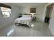 Bright bedroom showcases a plush bed, accent tables, ample natural light, and sleek, glossy tile floors at 23442 Harper Ave, Punta Gorda, FL 33980