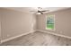 Bright bedroom showcasing hardwood floors, base molding, neutral gray walls, and a large window at 27260 Porto Nacional Dr, Punta Gorda, FL 33983