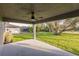 Covered patio with ceiling fan offers serene backyard view of lush lawn and mature trees at 27260 Porto Nacional Dr, Punta Gorda, FL 33983