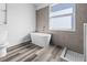 Stylish bathroom showcasing a modern freestanding tub, gray tiled walls, and luxury vinyl plank floors at 3297 Swanee Rd, Punta Gorda, FL 33980