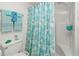 Bright bathroom featuring a shower with a tropical curtain and decorative turquoise towels at 3310 Loveland Blvd # 1906, Punta Gorda, FL 33980