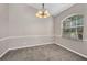 Cozy dining room featuring neutral walls, plush carpet, a charming chandelier, and a bright arched window at 4331 Marcella Ter, North Port, FL 34286