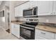 Kitchen featuring white cabinets, stainless steel microwave and range, and granite countertops at 4331 Marcella Ter, North Port, FL 34286