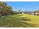 Large backyard showcasing sprawling lawn, mature trees, and a bird bath at 4420 Larkspur Ct, Port Charlotte, FL 33948