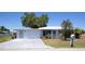 Charming home featuring a brick driveway, a well-maintained lawn, and a cheerful light blue front door at 458 Azalea Nw Ave, Port Charlotte, FL 33952