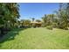 Lush backyard view of tropical landscaping and green grass surrounding this beautiful home at 552 Mccabe St, Port Charlotte, FL 33953