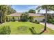 Charming yellow home with well-manicured lawn and lush tropical landscaping with palms at 552 Mccabe St, Port Charlotte, FL 33953