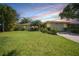 Inviting single-story home with a lush green lawn and mature landscaping at sunset at 552 Mccabe St, Port Charlotte, FL 33953