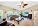 Bright living room with a vaulted ceiling, ceiling fan, large TV, and view of the outdoors at 552 Mccabe St, Port Charlotte, FL 33953
