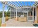 Outdoor kitchen includes built-in grill, pergola, and views of lake at 624 Planters Manor Way, Bradenton, FL 34212