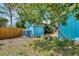 Backyard featuring storage tanks, green shed, wood fence, and mature trees for privacy at 1137 Ponderosa Rd, Venice, FL 34293