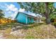 Exterior side view of a blue home with a brick patio, yard, and a mature tree at 1137 Ponderosa Rd, Venice, FL 34293
