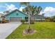 Charming home with a lush green lawn, mature landscaping, and blue exterior at 1137 Ponderosa Rd, Venice, FL 34293