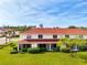 Exterior view featuring lush landscaping, and the red roof and neutral color scheme of the property at 1156 Jonah Dr, North Port, FL 34289