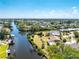 Aerial view of a waterfront community with homes on canals and boat docks under a clear blue sky at 18584 Alphonse Cir, Port Charlotte, FL 33948