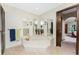Spacious bathroom featuring a soaking tub, mirrors, decorative sconces, and an adjacent bedroom at 18584 Alphonse Cir, Port Charlotte, FL 33948