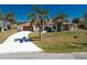 Inviting home with mature trees, a clean white driveway and lush landscaping at 18584 Alphonse Cir, Port Charlotte, FL 33948