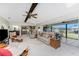 Bright living room with neutral carpet, ceiling fan, skylight, and sliding glass doors to the enclosed lanai at 18584 Alphonse Cir, Port Charlotte, FL 33948